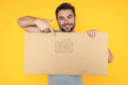Photo for Handsome man holding empty board and pointing finger on board. Guy showing blank board with copyspace. Idea and offer. Your advertisement. Blank advertising board with empty space for text, mockup - Royalty Free Image