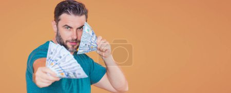 Téléchargez les photos : Homme tenir de l'argent sur fond de bannière isolée studio beige. Un riche en costume avec des billets en dollars. Homme d'affaires prospère avec des billets en dollars - en image libre de droit