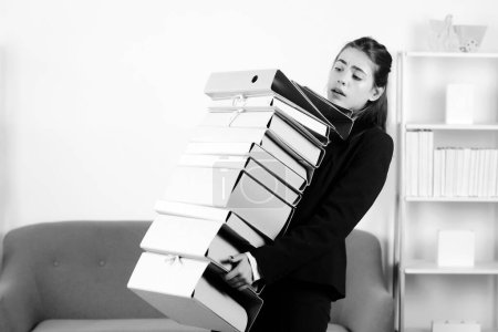 Foto de Mujer de negocios molesto sosteniendo muchas carpetas con los documentos, chica secretaria infeliz trabajando horas extras en la oficina. Solución de problemas - Imagen libre de derechos