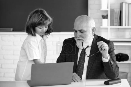 Photo for Teacher help to learn. Happy lessons. Back to school. Education and learning. Pupil and teacher with laptop. Teacher with schoolboy in classroom - Royalty Free Image