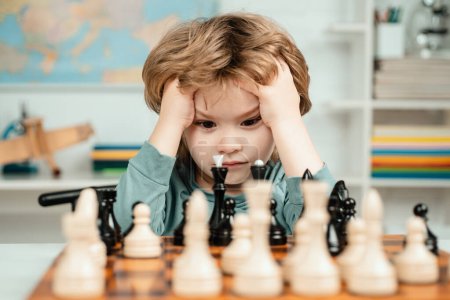 Téléchargez les photos : Garçon penser ou planifier sur le jeu d'échecs, style vintage pour le concept de l'éducation. L'école d'échecs. Garçon enfant jouer aux échecs à la maison - en image libre de droit
