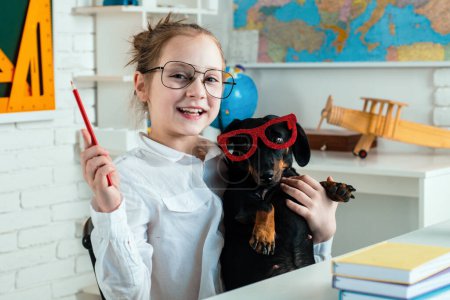 Photo for Funny puppi and pupil. Child girl with puppi. Happy smiling kid go back to school. Funny education. Funny puppy in glasses - Royalty Free Image