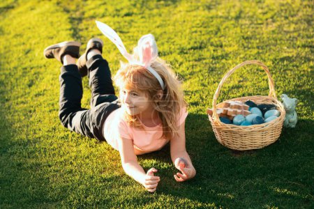 Photo for Children celebrating easter. Kid in rabbit costume with bunny ears outdoor. Easter kids with bunny ears and on grass background - Royalty Free Image