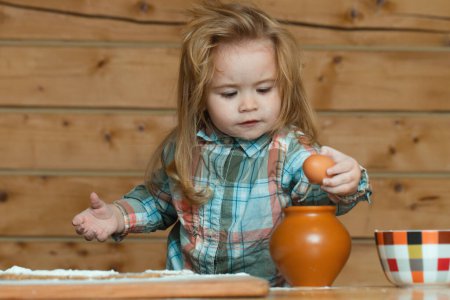 Foto de Niño en la cocina cocinando, jugando con huevos. Comida para bebés, desayunos familiares, juegos infantiles con utensilios de cocina. Niño bebé para romper el huevo - Imagen libre de derechos