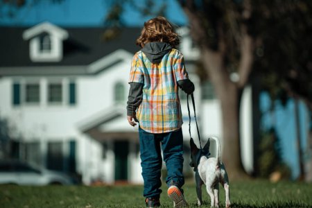 Foto de Un chico paseando con un cachorro. Divertido niño jugando con su perro en el parque - Imagen libre de derechos