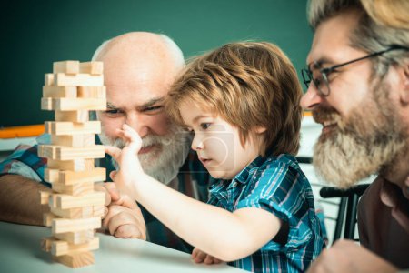 Photo for Three generations of active men playing in living room. Grandfather father and son spending weekend together. Head shot portrait smiling grandfather, father and preschool son - Royalty Free Image