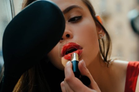 Téléchargez les photos : Maquillage en marche. Mode de vie en ville. Sexy girl avec des lèvres rouges mettre rouge à lèvres regardant dans un miroir de moto. Vogue de rue - en image libre de droit