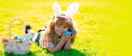 Photo for Easter banner, mockup copy space, poster flyer header for website template. Child boy hunting easter eggs, laying on grass. Kid in rabbit bunny ears outdoor - Royalty Free Image