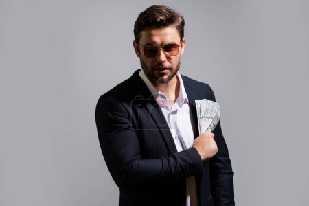 Photo for Man showing cash money in dollar banknotes. Portrait of business man isolated on gray studio background. Successful winner celebrating success or victory with money bills - Royalty Free Image