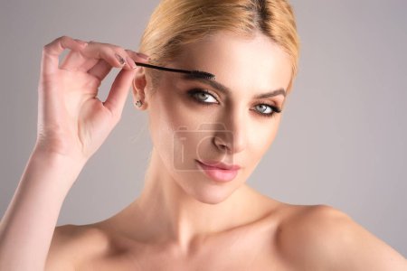 Téléchargez les photos : Modèle féminin façonnant les sourcils bruns. Œil de femme avec de beaux sourcils. Sourcil en forme parfaite, cils avec pinceau gel pour sourcils. Peindre les sourcils - en image libre de droit