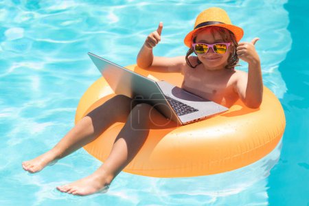 Photo for Child swimming on an inflatable ring with a laptop water pool. Funny kids summer face. Child with laptop in swimming pool in summer day - Royalty Free Image