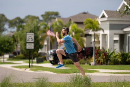 Foto de Hombre corriendo corriendo haciendo ejercicio al aire libre. Hombre atleta apto corriendo en el vecindario americano. Ajuste deportivo caucásico masculino, modelo deportivo de fitness que trabaja fuera en longitud completa - Imagen libre de derechos