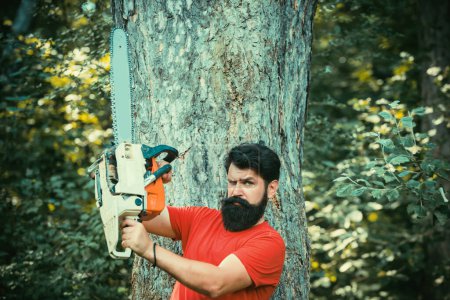 Foto de Un joven guapo con barba lleva un árbol. La deforestación es una de las principales causas de degradación de la tierra y desestabilización de los ecosistemas naturales - Imagen libre de derechos