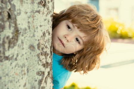 Photo for Little kid hide by tree. Hide and seek. Peekaboo - Royalty Free Image