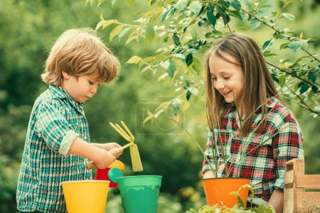 Photo for Kids planting flowers in pot. Two Happy children farmers working with spud on spring field - Royalty Free Image