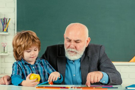 Photo for Learning and education concept. Man with old teacher learning in class on color background. Cute little preschool Man boy with Grandfather in a classroom - Royalty Free Image