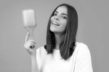 Photo for Girl combing hair. Beautiful young woman holding comb straightened hair - Royalty Free Image