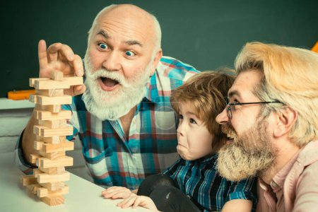 Foto de Riendo abuelo con hijo y nieto relajante pasar el fin de semana en casa. feliz hombre familia tener divertido juntos y jugando jenga - Imagen libre de derechos