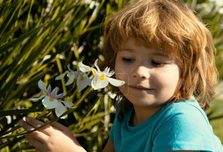 Foto de Feliz infancia. Primavera niño alergie olfatea flor floreciente. Lindo niño en el jardín de flores - Imagen libre de derechos