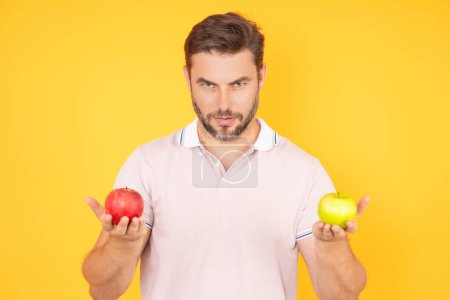 Photo for Biting apple concept. Portrait of a young man eating apple isolated over yellow background. Healthy apple fruit for natural vitamin, dieting and vegan. Studio portrait of hispanic guy eat apple - Royalty Free Image