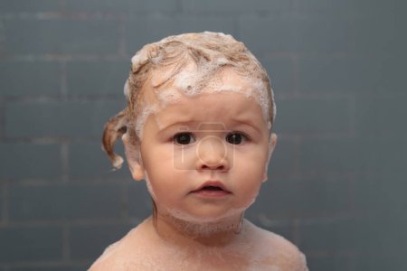Téléchargez les photos : Joyeux bébé drôle baigné dans le bain. Les enfants drôles font face de près. Bain d'enfant dans la baignoire - en image libre de droit