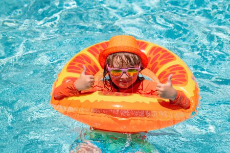 Foto de Salpicaduras de niños en la piscina. Nadar actividad deportiva acuática en vacaciones de verano con niños. Juguetes para niños - Imagen libre de derechos