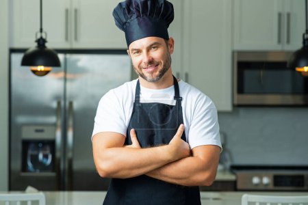 Téléchargez les photos : Chef cuisinier boulanger. Chef masculin millénaire en uniforme de chef. Chef cuisinier cuisinier sur cuisine. Chef cuisinier en chapeau et tablier - en image libre de droit