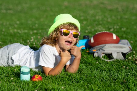 Photo for Child having fun outside. Child playing in garden. Happy little boy lying on the grass at the spring day - Royalty Free Image