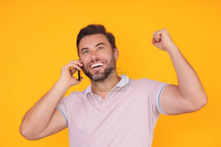 Photo for Excited man in t-shirt using mobile phone isolated on studio background. Portrait of confidence middle aged millennial hispanic man using cellphone. Guy with smartphone isolated studio background - Royalty Free Image
