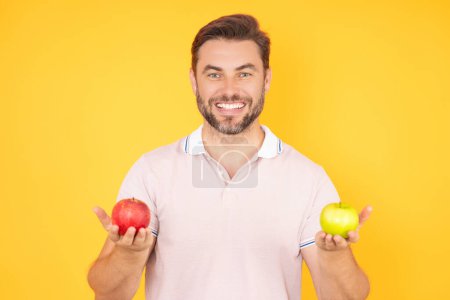 Stomatologie-Konzept. Mann mit perfektem Lächeln hält Apfel auf isoliertem Studiohintergrund. Der Mensch isst grünen Apfel. Porträt eines jungen, schönen, glücklich lächelnden Mannes mit Äpfeln. Gesunde Ernährung