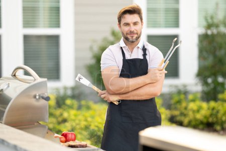 Téléchargez les photos : Chef préparant le barbecue. Cuire la viande masculine sur le barbecue grill. Homme cuisinant de la viande sur le barbecue pour le dîner familial d'été à l'arrière-cour de la maison - en image libre de droit