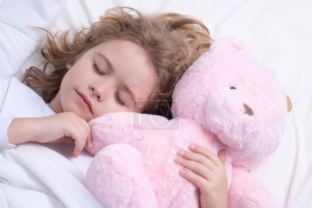 Foto de El sueño diario. Lindo niño duerme con un oso de peluche de juguete en la cama. Niña dormida - Imagen libre de derechos