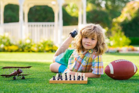 Photo for Dream kids and childhood concept. Kid laying on grass enjoy summer lifestyle. Child chessman play chess game, checkmate outdoor - Royalty Free Image