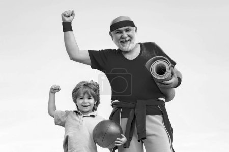 Photo for Father and child training together. Grandfather giving grandson ride on back in park. Healthy life and sport concept. Preparing for morning workout in the park - Royalty Free Image
