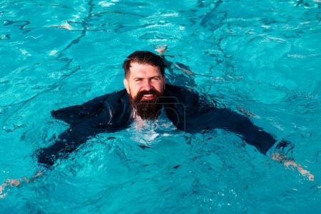 Foto de Empresario nadando en traje en la piscina. Hombre divertido y loco en la piscina. Hombre de negocios divirtiéndose junto a la piscina - Imagen libre de derechos