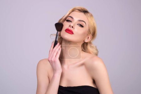 Téléchargez les photos : Beautiful woman applying make-up powder on the cheek. Cosmetic powder brush. Perfect skin and natural makeup - en image libre de droit