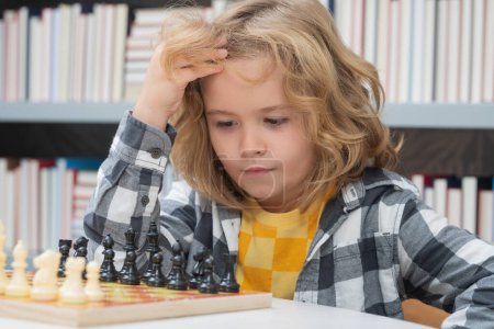 Téléchargez les photos : L'école d'échecs. Un gamin joue aux échecs. Enfant pensant. Jeu d'échecs pour les enfants. Intelligent, intelligent et intelligent garçon d'école - en image libre de droit