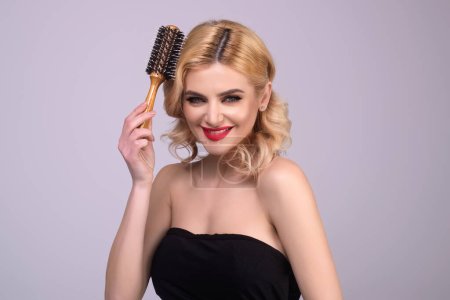 Photo for Beautiful model girl with comb brushing hair. Beauty woman with straight hair on studio background. Woman holding hairbrush near face. Healthy hair. Hairstyle and hair care concept. Shiny hairs - Royalty Free Image