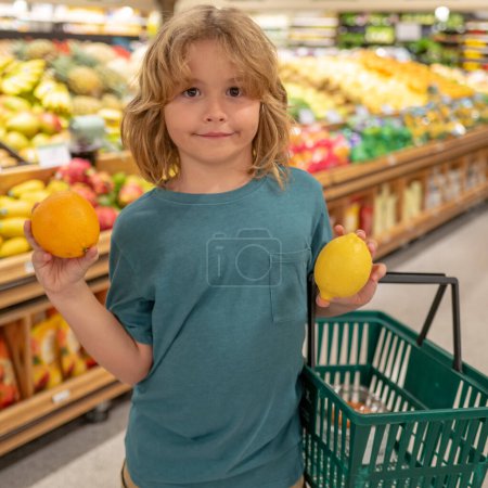 Foto de Niño con limón y naranja. Un chico en una tienda de comida o en un supermercado. Un niño yendo de compras. Comida saludable para niños - Imagen libre de derechos