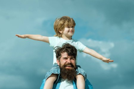 Foto de Padre e hijo jugando juntos. El niño se sienta sobre los hombros de su padre. Tiempo en familia - Imagen libre de derechos
