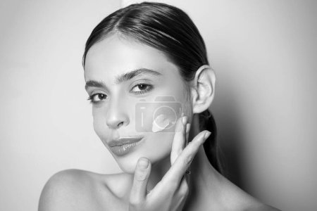 Photo for Beautiful woman spreading cream on her face. Skin cream concept. Facial care for female. Keep skin hydrated regularly moisturizing cream. Fresh healthy skin concept. Taking good care of her skin. - Royalty Free Image