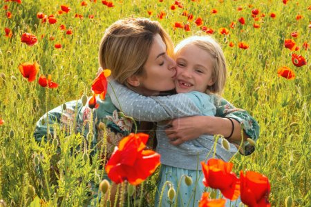 Foto de Madre e hija abrazándose en el campo de amapola floreciente. Vacaciones familiares de verano en la naturaleza. Verano en el prado de amapolas con flores poppys - Imagen libre de derechos