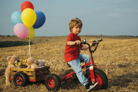 Téléchargez les photos : Enfant drôle avec vélo vintage dans une route de campagne. Concept de voyage et vacances. Enfant rêve de voyager - en image libre de droit