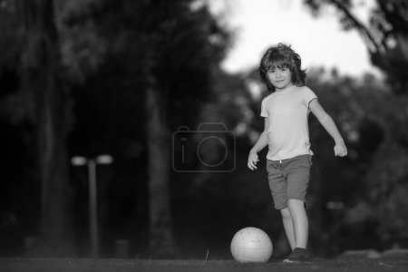 Foto de Niño jugando al fútbol en el campo con pelota de fútbol. Concepto de deporte infantil. Niño jugando al fútbol en el parque infantil - Imagen libre de derechos