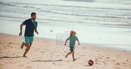 Foto de Padre e hijo juegan fútbol o fútbol en la playa en las vacaciones familiares de verano. Papá y el niño jugando al aire libre - Imagen libre de derechos