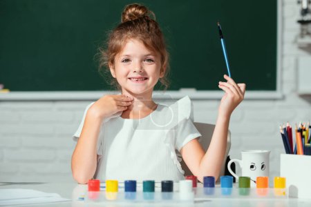 Photo for Cute little girl child painting with paints color and brush. Kids creative growth. Drawing lesson in school - Royalty Free Image