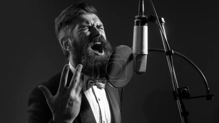 Téléchargez les photos : Singer interprète une chanson avec un microphone tout en enregistrant dans un studio de musique. Musique classique - en image libre de droit