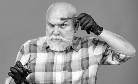 Foto de Peluquero senior. Hombre barbudo, hombre barbudo. Retrato de un elegante barbero con barba blanca. Tijeras de peluquero y navaja de afeitar, peluquería. Peluquería vintage, afeitado - Imagen libre de derechos