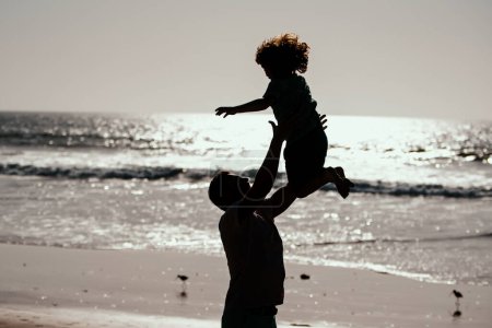 Foto de Padre vomita hijo contra el cielo azul. Papá tirando niño, silueta al atardecer. Concepto generación hombres - Imagen libre de derechos