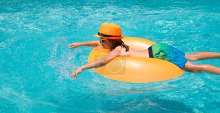Téléchargez les photos : Petite fille mignonne et souriante dans les lunettes de soleil et chapeau d'été dans la piscine dans la journée ensoleillée. Enfants nageant sur anneau flottant dans la piscine. Portrait d'été enfants - en image libre de droit